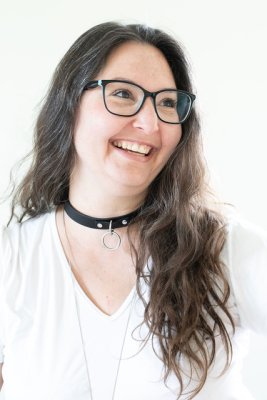 A headshot-style photo of lily smiling, set against a white background, her long brown hair brushed to the side.